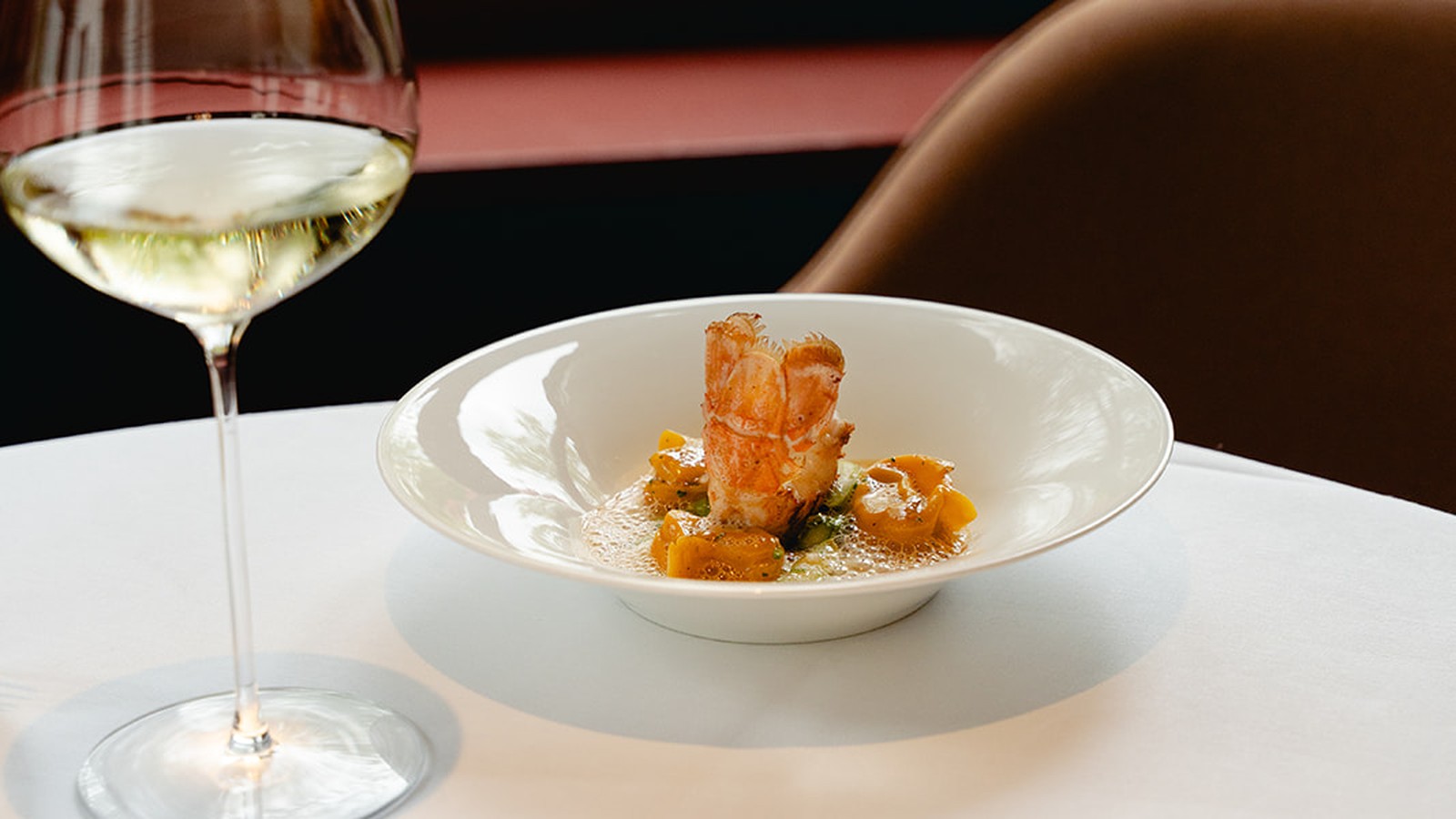 Gerecht met kreeft en een glas wijn op een gedekte tafel bij Brabohoeve